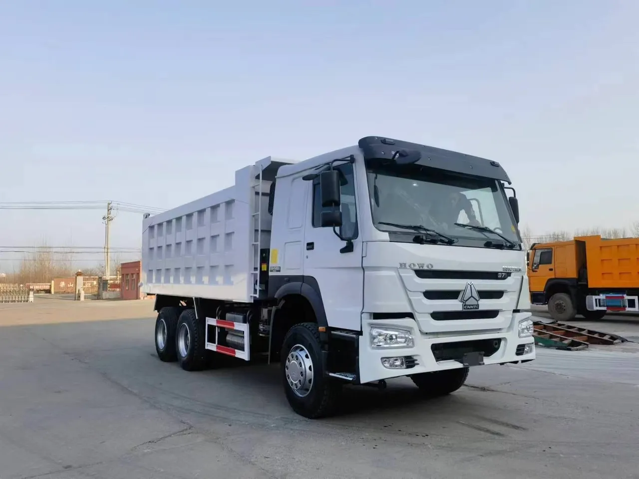 قلاب 6x4 بحمولة 20 طن محمَّل في الميناء جاهز للتصدير، شاحنة HOWO قلاب باللون البرتقالي